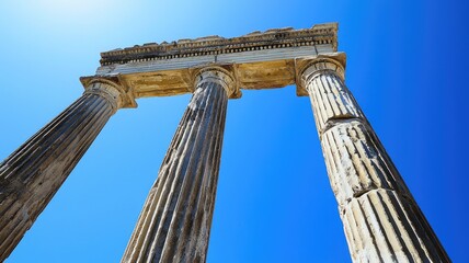 Naklejka premium Ancient columns rise against a clear blue sky, showcasing classical architecture and historical elegance in a stunning perspective.