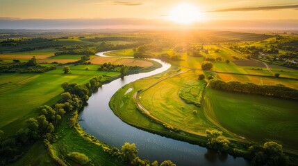 Fototapeta premium golden hour aerial view of a rural landscape with a river winding through it, the sun's rays casting a warm light on the water and fields, creating a peaceful and idyllic scene, with copy space for
