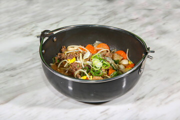 A pot of beef bulgogi, with tender slices of marinated beef simmering in a rich broth. The savory aroma and vibrant vegetables enhance the comforting, hearty dish.