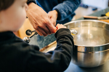 Close-up of a child and an adult measuring ingredients