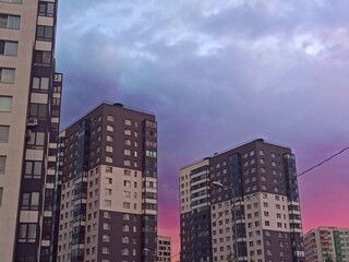 Obraz premium Modern apartment buildings on a background of blue sky with clouds at sunset