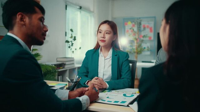 Young businesswoman leads a meeting with two colleagues in an office. They are discussing business strategy and analyzing financial data