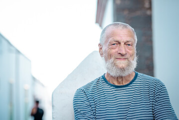 Portrait of an elderly man smiling in the park during his leisure time. This mature gentleman exudes serenity and happiness, showcasing a healthy and fulfilling lifestyle while embracing the joys 