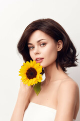 Beautiful young woman holds a sunflower on a white background