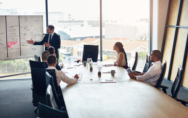 Boardroom, presentation and people in meeting, white board and controller with financial report and teamwork. Business, speaker and group in office, listening and discussion of sales and analysis © ThurstanJam/peopleimages.com