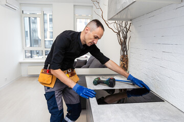 craftsman installs hob in kitchen. Household Appliance Installation Services Concept