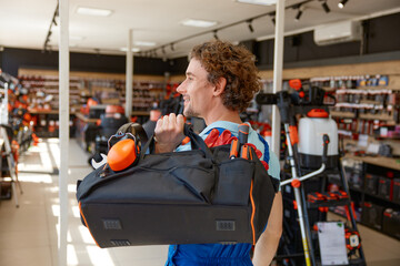 Repairman walking with storage bag filled modern tools at hardware store