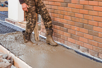 Builder pour and level wet ready-mix concrete into formwork during construction of a new blind area