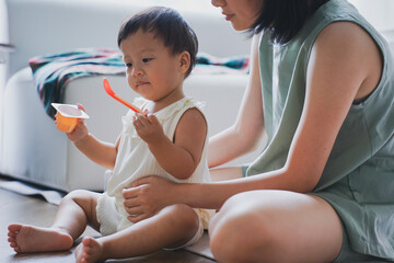 Asian woman feeding her child yogurt
