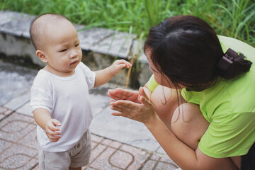 Young Asian woman playing with her son in the park