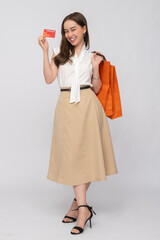 Stylish woman enjoying a successful shopping spree, proudly holding her credit card and vibrant shopping bags, symbolizing modern consumer confidence