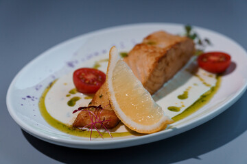 Gourmet Grilled Salmon with Lemon Wedge and Cherry Tomatoes on Elegant White Plate with Artistic Sauce