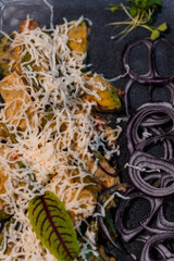Gourmet Vegetable Stir Fry with Grated Cheese and Fresh Onions on Dark Plate