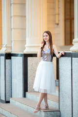 Fototapeta premium Young smiling girl walking around the city. Girl with light brown hair in summer clothes posing against the background of ancient historical buildings of Venetian style.