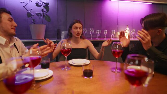 Pretty young woman talking story to friends in meeting in restaurant in weekend . Group of diverse young people dinning together in restaurant in Friday night, cheering and applauding to girlfriend