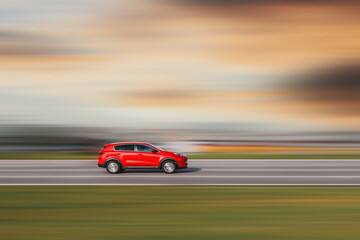 Red car. A red crossover is driving down the street at high speed. Background blurred at speed