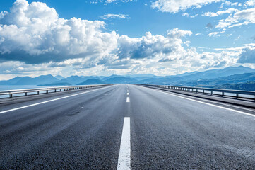 Empty asphalt highway leading to the mountains by the sea