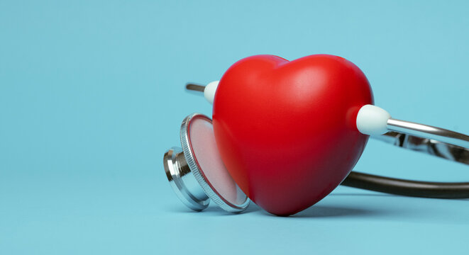 Red heart shape exercise ball with doctor physician's stethoscope on blue background, hospital life insurance concept, world heart health day. doctor day
