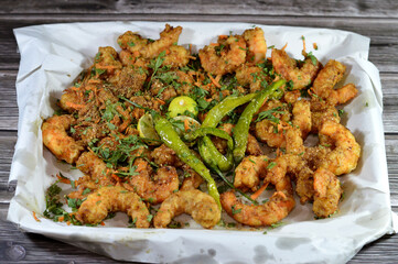 Fried shrimps with parsley, fried green chili pepper and lemon, crunchy fried peeled shrimps seasoned with salt, pepper and spices, a shrimp is a crustacean form of shellfish belongs to the Caridea