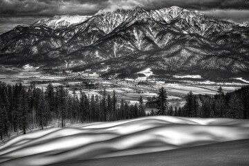 Snow-covered mountains rise majestically behind a sweeping valley with soft, rolling snowdrifts in the foreground.