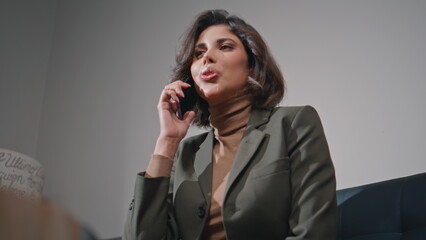 Smiling businesswoman talking cellphone in office lobby closeup. Executive call