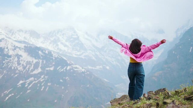 4K shot of Indian Girl raising her hands up with emotions of joy and sense of satisfaction. Girl on top of the mountain celebrating summit. The concept of achieving success. Happy and drunk on life
