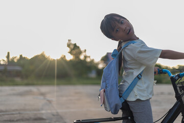 A young girl is riding a bicycle with a backpack on her back