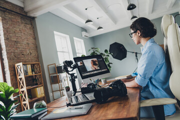 Photo of positive lady photographer dressed shirt retouching portraits modern device indoors workstation workshop