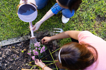Watering flowers in garden, asian mother and daughter gardening together, bonding activity