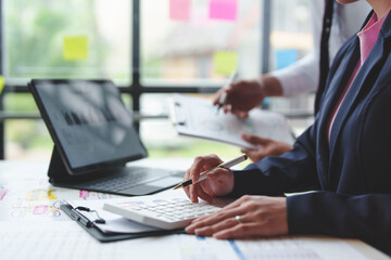 Two businessmen working in finance Online marketing on a laptop. Calculate, analyze, graph investment costs. Real estate and taxes on work table in modern office together.