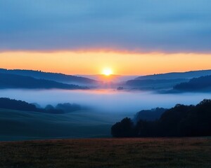 Obraz premium A stunning sunrise over a misty valley, with vibrant colors illuminating the sky and soft fog covering the landscape.