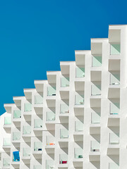 Minimalist photo of resort hotel building with repeating patterns of windows and architectural elements and blue sky in the background © Andrei H