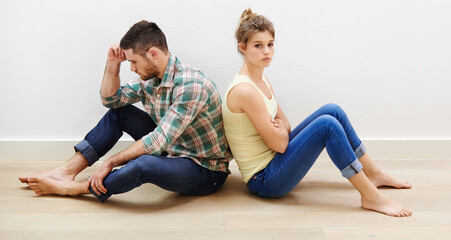 Couple, sad and conflict in home with backs, fighting and toxic relationship with anxiety. Man overthinking, woman portrait and sitting on floor with depression, frustrated and argue in living room