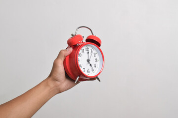 Vintage red alarm clock in hand. Round red alarm clock isolated on white background shows 5 am