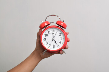 Vintage red alarm clock in hand. Round red alarm clock isolated on white background shows 5 am