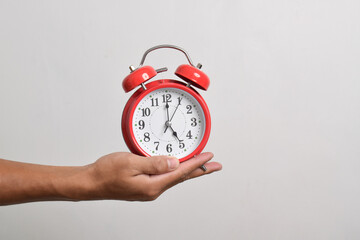 Vintage red alarm clock in hand. Round red alarm clock isolated on white background shows 5 am