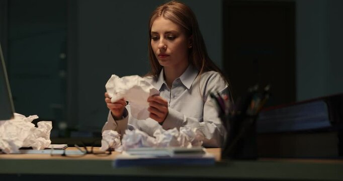 Anxious businesswoman uncrumples paper sheets seeking written data at table. Female employee expresses frustration with difficult task in office