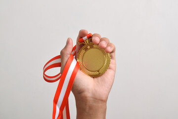 Hand holding gold medal isolated on white background. The winner and successful concept