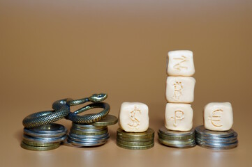 Icons of bitcoin, dollar, ruble and euro with arrows, the concept of currency exchange. Next to it is a snake figurine with coins.