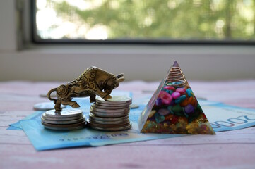 A bull statuette with coins, a pyramid and banknotes. Financial success.