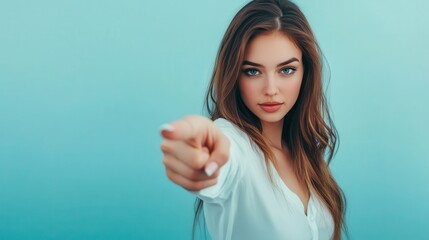 Fototapeta premium Confident woman pointing at camera with serious expression, turquoise background, concept of choice and empowerment.