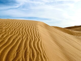Minimalist photography of golden dunes against a bright blue sky next to the ocean. Dunas Maspalomas Gran Canaria, Spain