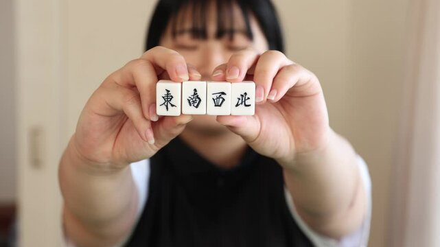 麻雀牌を持つ20代のアジア人女性 東南西北
