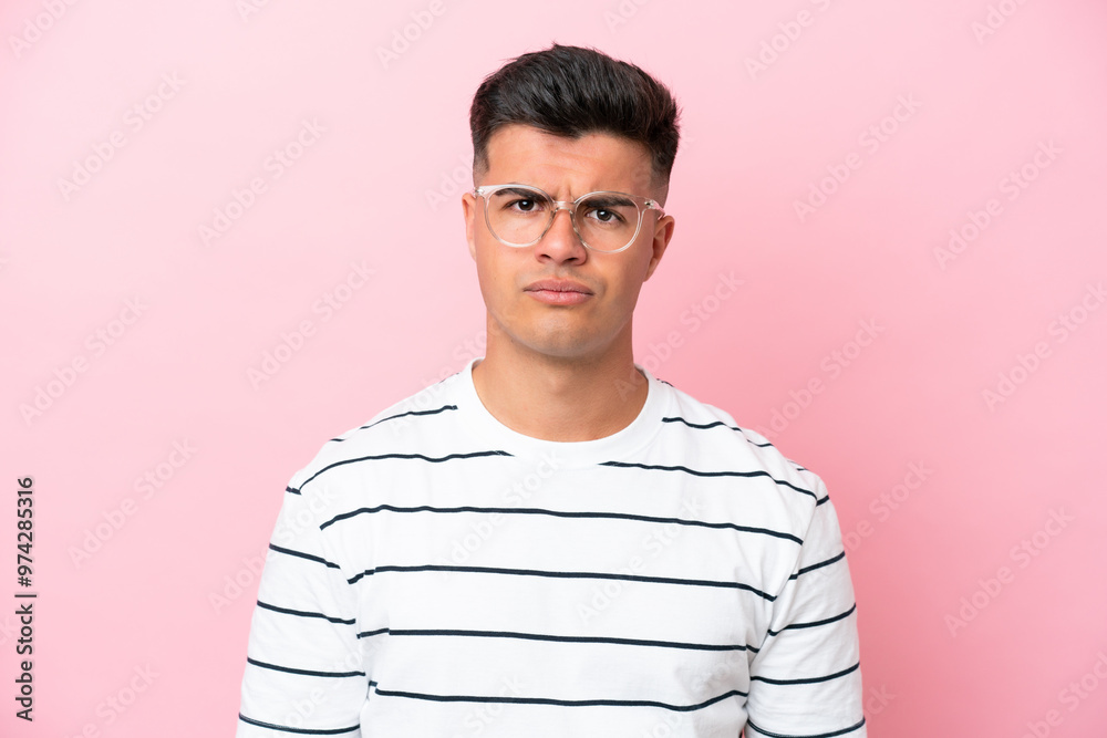 Wall mural Young caucasian handsome man isolated on pink background With glasses