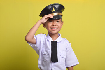 Little Asian boy Airplane pilot salute isolated on yellow background. Little boy dreams of becoming an airplane pilot.