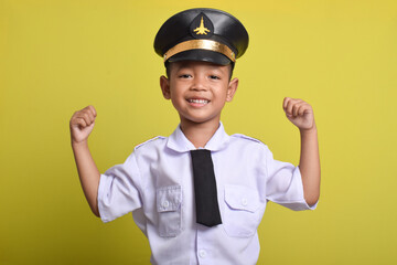 Little Asian boy Airplane pilot isolated on yellow background doing strong movement. Little boy dreams of becoming an airplane pilot.