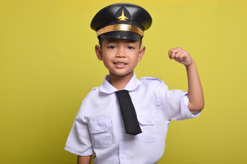 Little Asian boy Airplane pilot isolated on yellow background doing strong movement. Little boy dreams of becoming an airplane pilot.