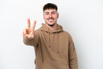 Fototapeta premium Young caucasian handsome man isolated on white background smiling and showing victory sign