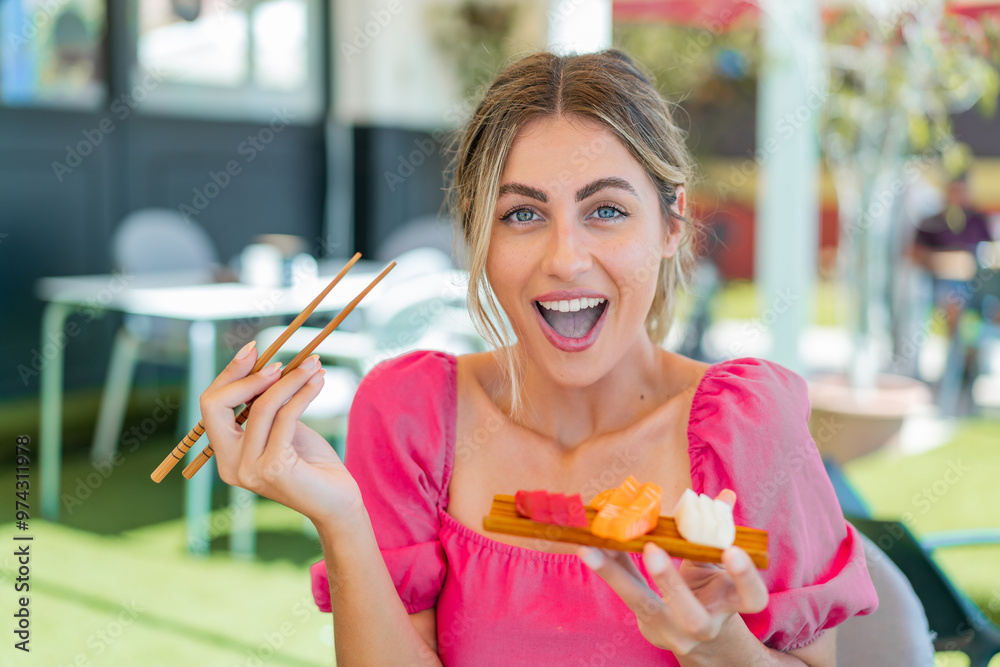 Wall mural young blonde woman holding sashimi at outdoors