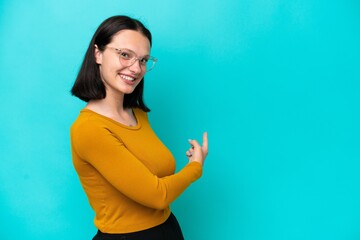 Fototapeta premium Young caucasian woman isolated on blue background pointing back
